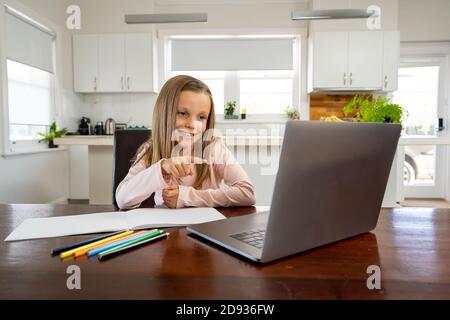 Bonne écolière sur ordinateur portable regardant la leçon en ligne apprendre à distance à la maison dans l'isolement. L'éducation, les quarantaines et les écoles rouvrant ou shuttin Banque D'Images