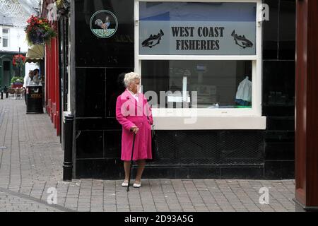 Femme en manteau rose à l'extérieur de West Coast Fisheries à Ayr, Ayrshire, Écosse, Royaume-Uni Banque D'Images
