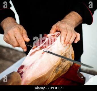 Le coupe-jambon professionnel Iberico ou Serrano coupe une tranche branche de porc avec un couteau à jambon Banque D'Images