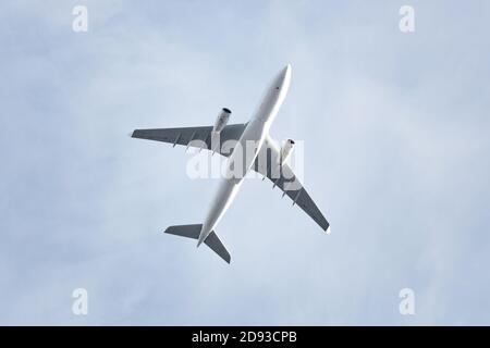 Voyages, transport, aviation. Avion passager volant contre un ciel bleu, vue de dessous Banque D'Images