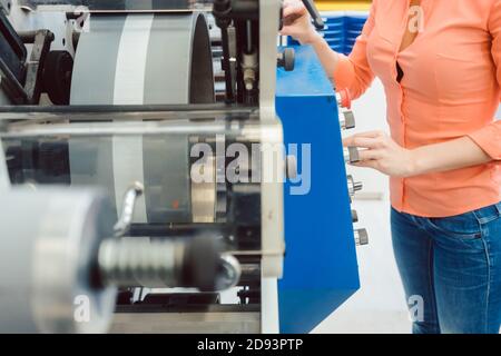 Femme appuyant sur le bouton de démarrage de la machine d'impression d'étiquettes Banque D'Images