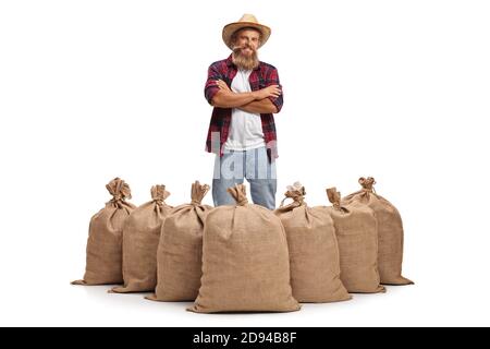 Fermier barbu debout derrière des sacs de burlap avec des pommes de terre isolées dessus arrière-plan blanc Banque D'Images