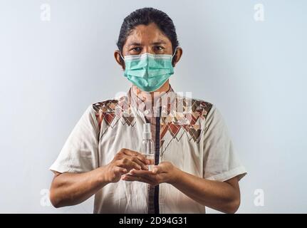 L'homme asiatique porte un masque chirurgical et tient un désinfectant pour les mains ou une bouteille anti-bactérienne. Virus pandémique concept Banque D'Images