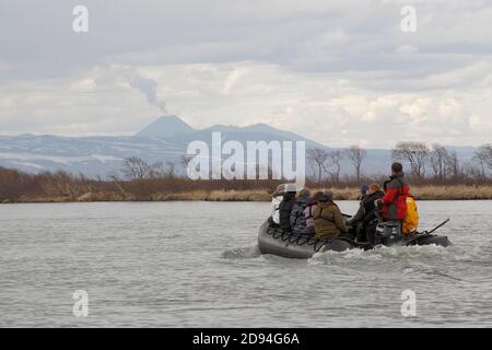 Touristes à Zodiac bateau en caoutchouc, fleuve Zhupoanova, (volcan fumeur à l'horizon), Kamchatka, Russie de l'est 31 mai 2012 Banque D'Images