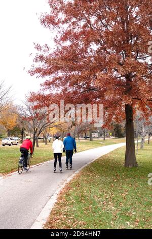 Les gens qui apprécient les couleurs de l'automne sur le sentier de randonnée et de vélo autour du lac BDE Maka Ska. Minneapolis Minnesota MN États-Unis Banque D'Images