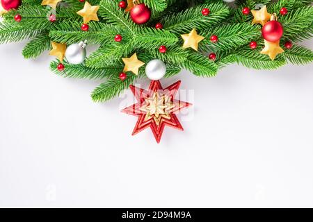 Guirlande de Noël branches de sapin boules décorées et étoiles confetti, vue du dessus de la tête décoration de Noël festive et ornements isolés sur le dos blanc Banque D'Images