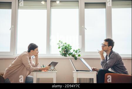 Photo vue latérale d'un couple caucasien regardant chacun d'autres et de penser tout en travaillant avec un ordinateur portable Banque D'Images