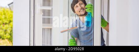 Un jeune homme nettoyant la fenêtre avec une BANNIÈRE de nettoyage de fenêtre, FORMAT LONG Banque D'Images