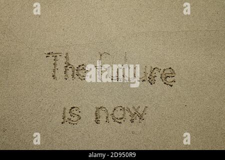 L'avenir est maintenant - l'avenir est maintenant, le texte de concept de technologie innovant écrit sur le sable Banque D'Images