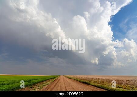 Paysage pittoresque avec des nuages de cumulonimbus au-dessus d'une route et d'un champ de terre près de Goodland, Kansas Banque D'Images