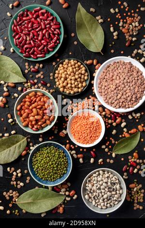 Diverses légumineuses, tiré du dessus sur un fond sombre. Lentilles, soja, pois chiches, haricots rouges, pois à yeux noirs et autres légumineuses, une étalée plate Banque D'Images