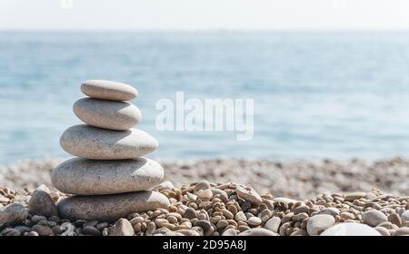 Ambiance zen et relax. Une pyramide de pierres sur la plage par temps clair et ensoleillé. Fond pour la méditation, le yoga et le massage Banque D'Images