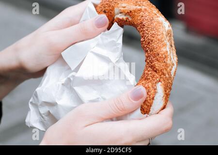 Simit turc traditionnel dans une main féminine. Bagel croustillant aux graines de sésame Banque D'Images