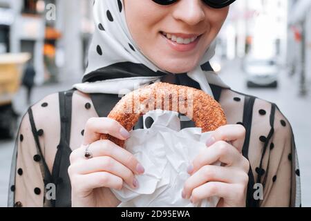 Mignonne jeune femme tenant dans la main le simit turc traditionnel dans une main femelle. Bagel croustillant aux graines de sésame Banque D'Images