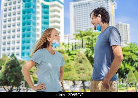 Un homme et une femme communiquent dans la rue avec des masques mal portés. Concept de port incorrect de masques médicaux Banque D'Images