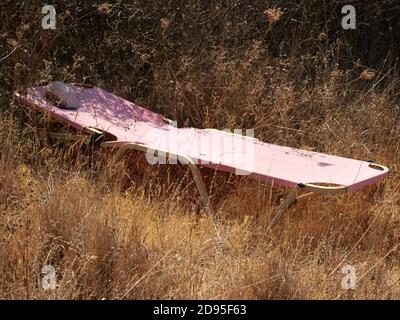 Ancienne chaise longue extérieure rose abandonnée dans un champ Banque D'Images