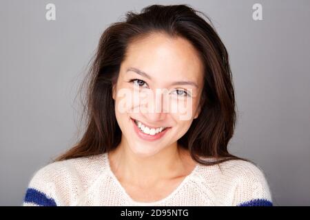 Gros plan sur le visage d'une jeune femme asiatique souriante sur fond gris Banque D'Images