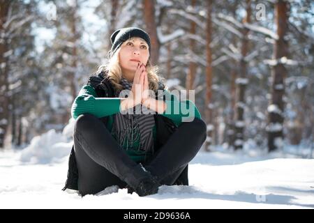 Lady repose dans une forêt enneigée dans une posture de yoga. Belle femme est assise en position lotus. Concept de méditation d'hiver. Banque D'Images