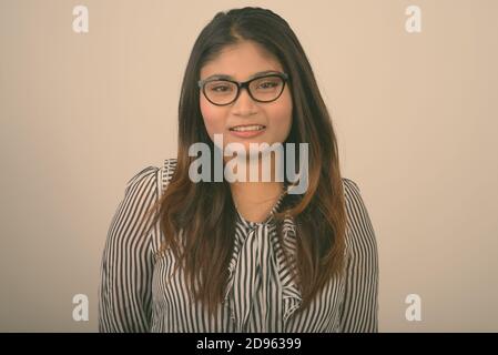 Close up of young happy businesswoman smiling persan gras tout en portant des lunettes contre l'arrière-plan gris Banque D'Images