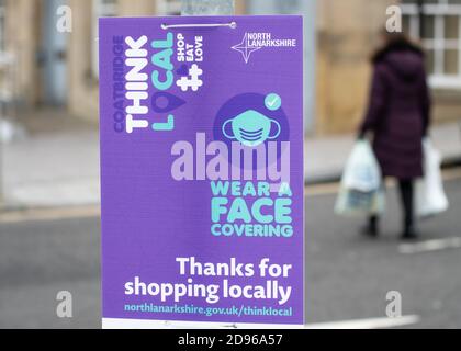 Coatbridge, North Lanarkshire, Écosse, Royaume-Uni pendant la pandémie du coronavirus - porter un visage couvrant grâce à l'achat de panneaux locaux Banque D'Images