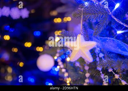 Étoile blanche suspendue sur un arbre de Noël, décorations de Noël la nuit, lumières de vacances blanches et dorées Banque D'Images