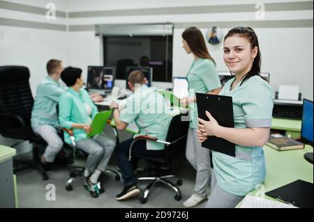 Thème médical .Portrait d'une femme médecin avec presse-papiers contre un groupe de médecins réunis dans le bureau de l'irm au centre de diagnostic de l'hôpital. Banque D'Images