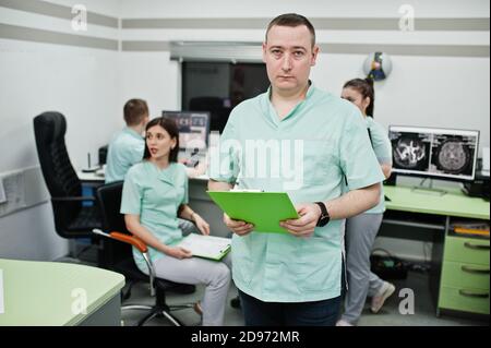 Thème médical .Portrait d'un médecin masculin avec presse-papiers contre un groupe de médecins réunis dans le bureau de l'irm au centre de diagnostic de l'hôpital. Banque D'Images