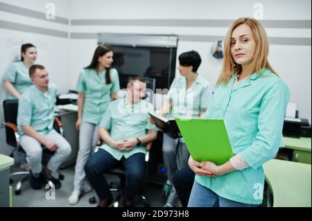 Thème médical .Portrait d'une femme médecin avec presse-papiers contre un groupe de médecins réunis dans le bureau de l'irm au centre de diagnostic de l'hôpital. Banque D'Images
