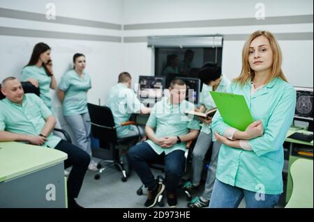 Thème médical .Portrait d'une femme médecin avec presse-papiers contre un groupe de médecins réunis dans le bureau de l'irm au centre de diagnostic de l'hôpital. Banque D'Images