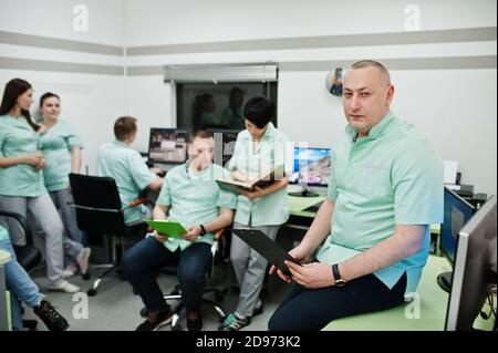 Thème médical .Portrait du médecin avec presse-papiers contre un groupe de médecins se rencontrant dans le bureau de l'irm au centre de diagnostic de l'hôpital. Banque D'Images