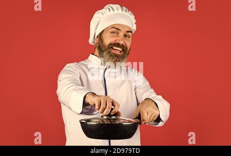 Petit-déjeuner fait maison. Cuisine comme pro. Repas savoureux et facile préparé à la maison. Récipient en céramique. Préparer la nourriture dans la cuisine. Concept de cuisine. Poêle à frire de haute qualité. Homme barbu cuisinier uniforme blanc. Banque D'Images