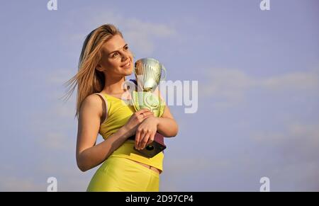 Prix Gold. Un athlète mignon récompensé par une tasse. Prix de la première place et succès. Fille a un trophée d'or. Femme a remporté le concours. Prix de la femme gagnant. Heureuse fille a remporté le trophée. Succès sportif. Banque D'Images