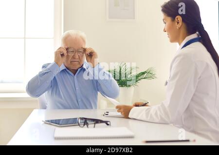 Homme âgé mettant ses lunettes pour lire sa prescription ou rapport de diagnostic Banque D'Images