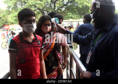 Un responsable de la sécurité vérifie la température corporelle des visiteurs à l'entrée du zoo national du Bangladesh après avoir rouvert à partir du 1er novembre suivant Banque D'Images