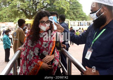 Un responsable de la sécurité vérifie la température corporelle des visiteurs à l'entrée du zoo national du Bangladesh après avoir rouvert à partir du 1er novembre suivant Banque D'Images