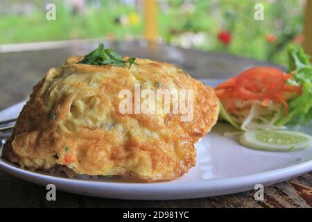 Riz blanc recouvert d'une omelette parfumée à la coriandre, servi avec des légumes frais et une sauce Chili pour plus de saveur. Banque D'Images