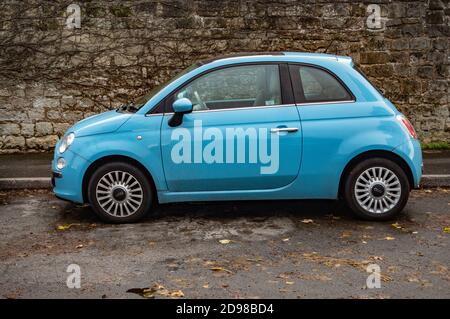 Petite voiture Fiat 500 bleue avec fond de mur en pierre Banque D'Images