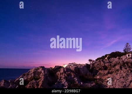 vue à l'aube du ciel pourpre avec étoiles et jetée rocheuse de majorque. vue spectaculaire et relaxante du coucher de soleil dans le port de porto colom avec mer et coucher de soleil Banque D'Images