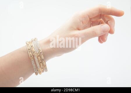 Vue latérale de la main féminine avec bracelets dorés sur le blanc Banque D'Images