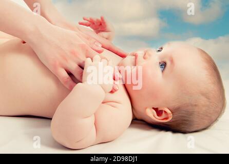 Sur fond ciel bleu ciel nuageux les mains de mères se touchent doucement son doux petit bébé adorable, vue de près enfant couché regardant la momie aimante. Concept de lov Banque D'Images