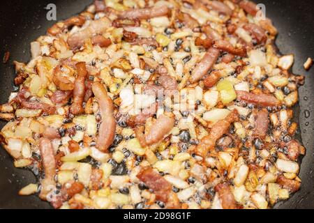Photo d'un délicieux lard de bacon avec des oignons. Frits dans de l'huile bouillante dans une casserole. Concept de cuisine. Gros plan Banque D'Images
