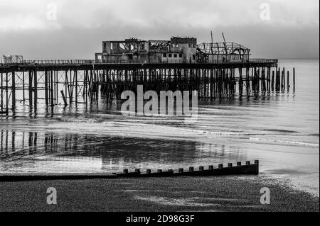 Vue monochrome du Gaunt et de l'épave tordue de Hastings Pier dans East Sussex, Angleterre, Royaume-Uni, photographiée sept mois après le feu dévastateur de 2010. La jetée victorienne, ouverte en 1872, a accueilli d'importants spectacles de rock et de pop dans les années 1960, dont Pink Floyd, Jimi Hendrix, les Rolling Stones et l'OMS. Un incendie a détruit le pavillon de la jetée Hastings de 2,000 places en 1972, la jetée a été fermée comme une structure dangereuse et l'incendie a détruit le 5 octobre 2010 ses bâtiments en bois restants. Les travaux de reconstruction ont été lancés en 2011 et la jetée a été rouverte en 2016. Banque D'Images