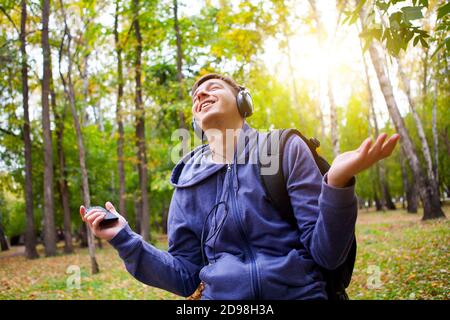 Joyeux jeune homme dans les écouteurs Ecouter la musique dans La forêt Banque D'Images
