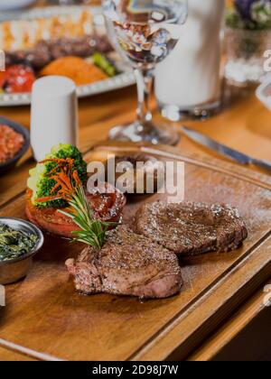 Steak grillé sur planche à découper en bois. Garniture aux champignons, aux tomates et aux épinards. Banque D'Images