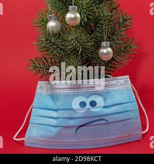 Arbre de Noël avec masque sur fond rouge Banque D'Images