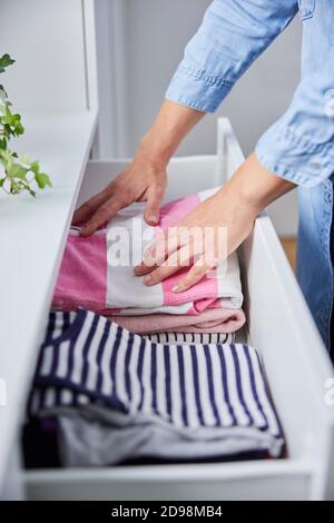 Gros plan de la femme qui replie les vêtements et les mordant Dans les tiroirs Banque D'Images