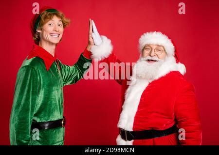 Photo de profil de deux hommes palmes de l'elf du père noël donner cinq vêtements x-mas costume manteau coiffures isolé couleur rouge arrière-plan Banque D'Images