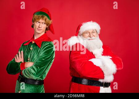 Photo de profil de deux hommes ont croisé les bras le sourire du père noël elf grenouille vêtements x-mas costume manteau coiffures isolé couleur rouge arrière-plan Banque D'Images