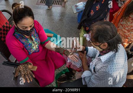 New Delhi, Inde. 3 novembre 2020. Une femme reçoit des dessins de henné sur ses mains avant le festival hindou Karwa Chauth à New Delhi, Inde, 3 novembre 2020. Karwa Chauth, un festival hindou traditionnel au cours duquel les femmes se marient rapidement un jour et offrent des prières à la lune pour le bien-être, la prospérité et la longévité de leurs maris. Crédit : Javed Dar/Xinhua/Alay Live News Banque D'Images