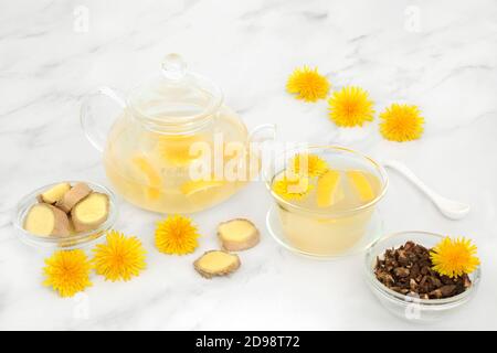 Épices au gingembre, fleurs de pissenlit et thé au citron pour un soutien immunitaire dans une théière en verre et une tasse avec racine de pissenlit séchée. Abaisse le cholestérol, la pression artérielle, Banque D'Images